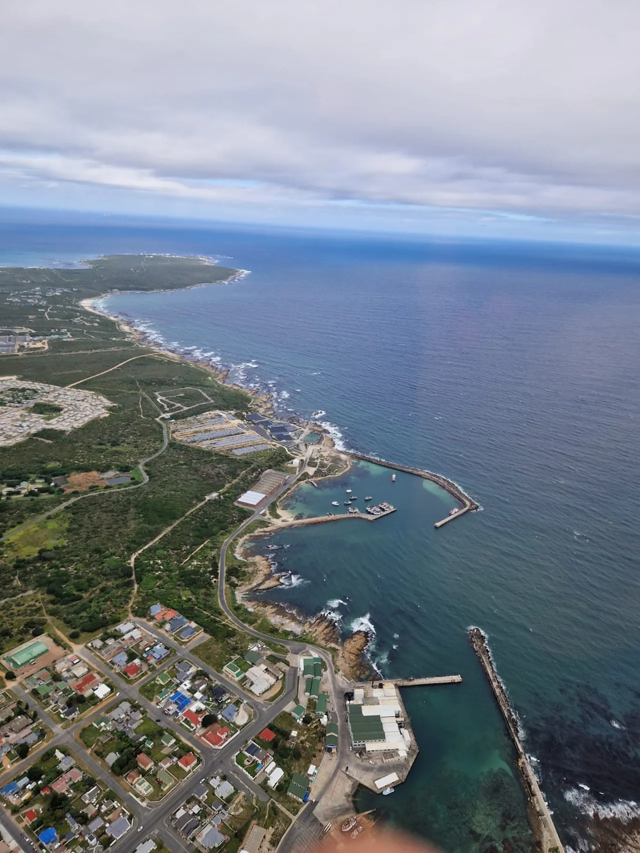 Rugged coastline, harbour and open ocean seen from a whale watching helicopter